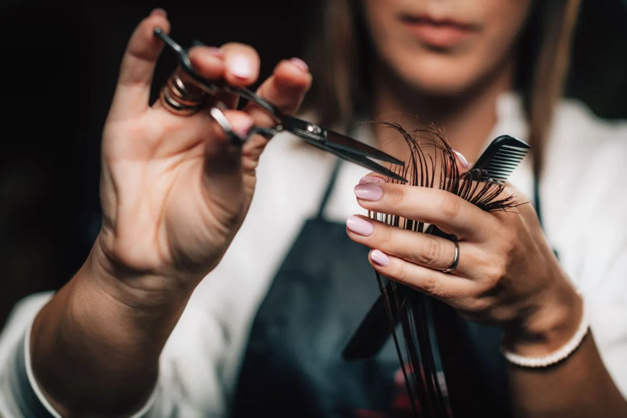 Friseurin schneidet Haarsträhnen präzise mit Schere und Kamm